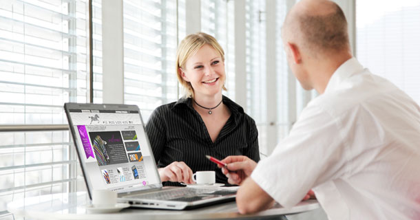 two people discussing next to a laptop