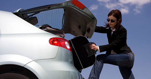 woman removing bag from car trunk